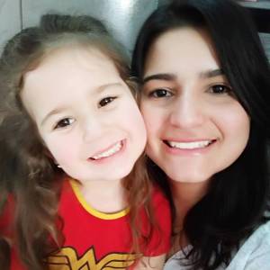 Filha, com a blusa da mulher maravilha, posando com a mãe para uma selfie