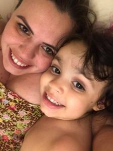 Mãe e filha deitadas, sorrindo, prontas para tirar uma foto