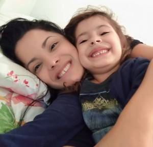 Mãe e filha com o mesmo sorrido, deitadas, tirando uma foto juntas