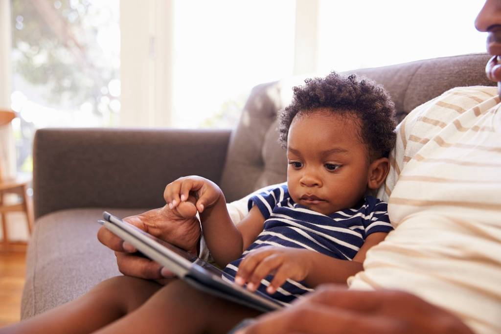 Criança usando o tablet com o pai