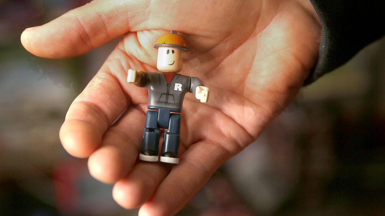 mão segurando bonequinho roblox