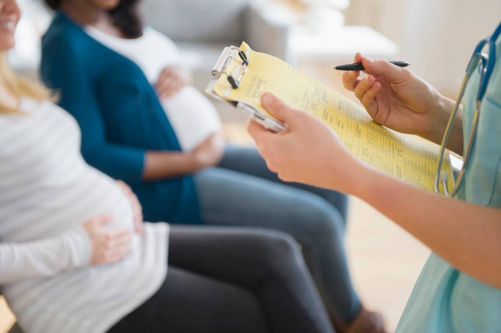 Enfermeira marcando prontuário médico perto de mulheres grávidas Lei 5.741: Revolução! Gestantes agora escolhem anestesia e tipo de parto
