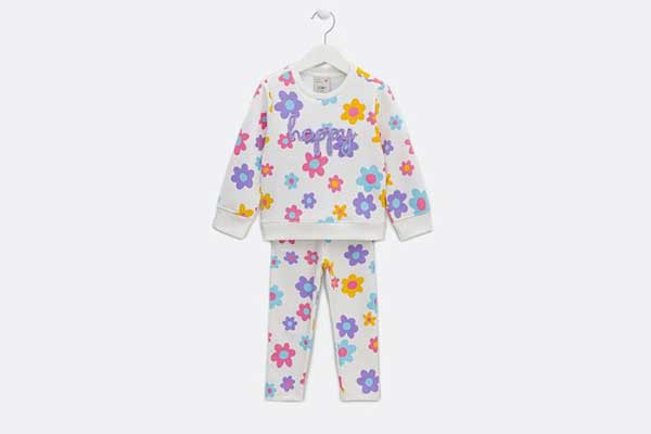 conjunto infantil de calça e blusa de manga comprida. O tecido é branco e tem estampas de flores coloridas