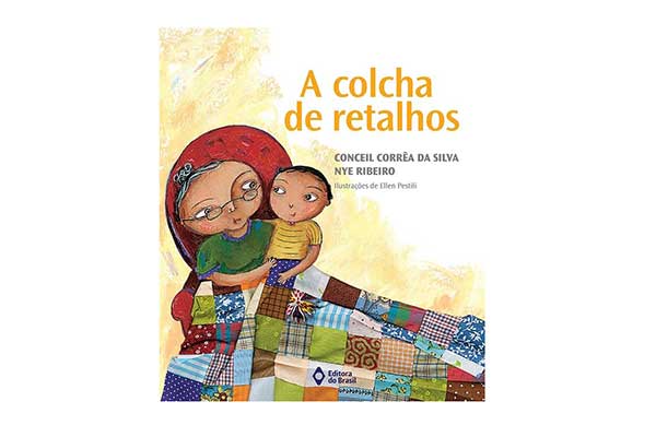 A-Colcha-de-Retalhos---Conceil-Corrêa-da-Silva-e-Nye-Ribeiro-(Editora-do-Brasil) capa do livro A Colcha de Retalhos, com ilustração de uma avó sentada em uma poltrona com o neto no colo. Eles estão cobertos por uma colcha de retalhos