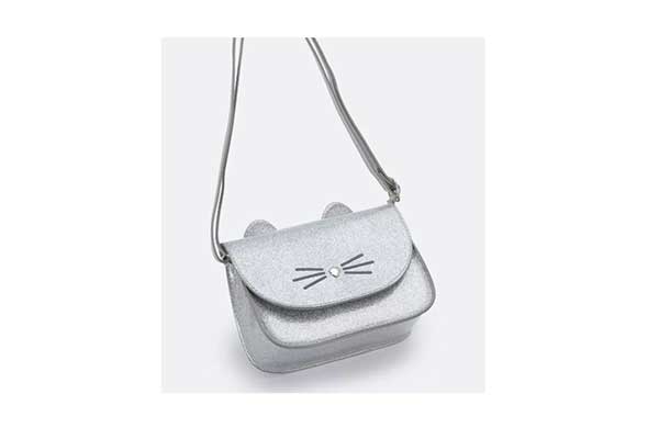 bolsa infantil prata. Ela é quadrada, tem orelhinhas na parte de cima e o desenho de bigodes de gato na parte da frente