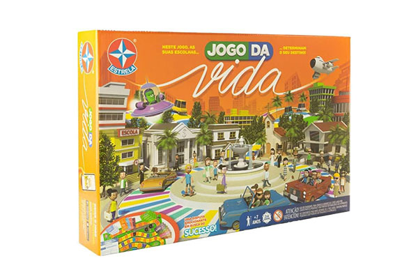 Caixa de papelão retangular, horizontal, do Jogo da Vida. Ela tem a ilustração de uma praça, com uma fonte no meio e a cidade em volta, por onde pessoas circulam